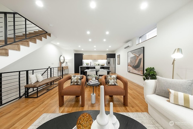 living room with a wall mounted AC and light wood-type flooring