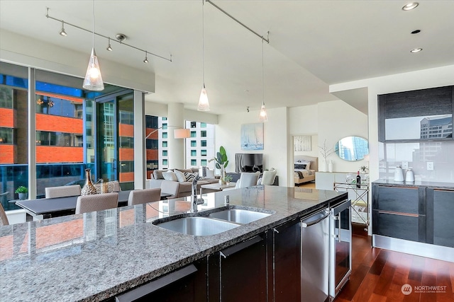 kitchen featuring light stone countertops, sink, pendant lighting, and dark wood-type flooring