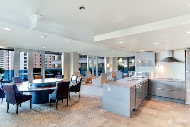 kitchen with wall chimney range hood, appliances with stainless steel finishes, hanging light fixtures, tasteful backsplash, and kitchen peninsula