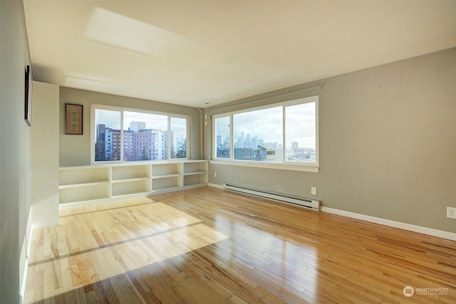 spare room with baseboard heating and light wood-type flooring