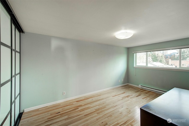 empty room with light hardwood / wood-style flooring and baseboard heating