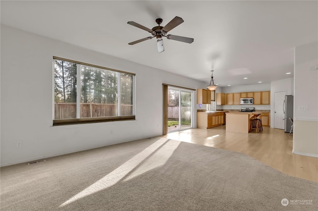 unfurnished living room with ceiling fan and light colored carpet