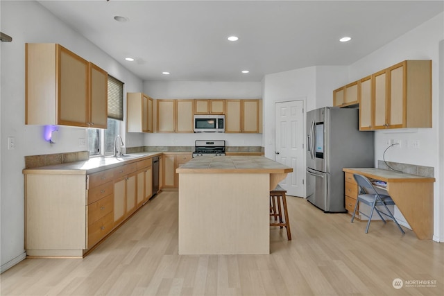 kitchen featuring a kitchen bar, light brown cabinets, a kitchen island, stainless steel appliances, and light hardwood / wood-style floors