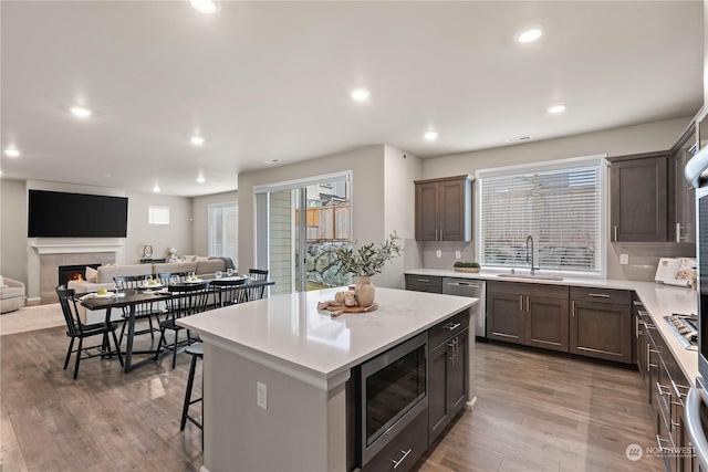 kitchen featuring a breakfast bar, sink, a center island, appliances with stainless steel finishes, and hardwood / wood-style floors