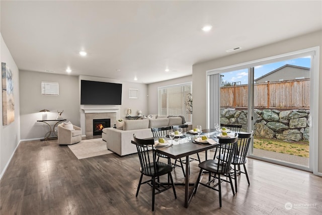 dining space featuring a tiled fireplace and wood-type flooring