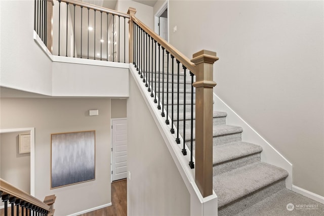 stairway featuring a towering ceiling and hardwood / wood-style floors