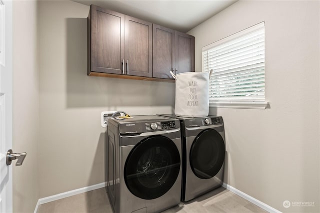 washroom featuring cabinets and washer and clothes dryer