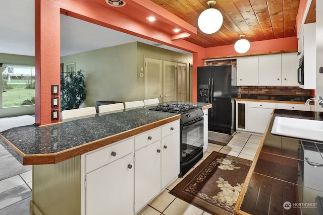 kitchen featuring sink, a breakfast bar area, black appliances, and white cabinets