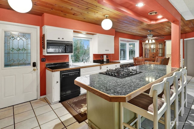 kitchen featuring a breakfast bar, black appliances, light tile patterned floors, kitchen peninsula, and white cabinets