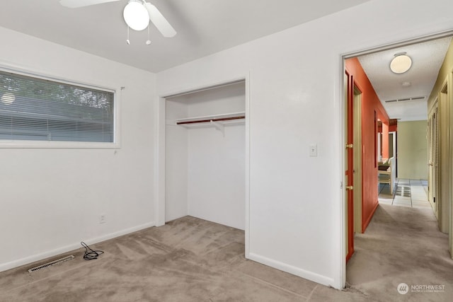 unfurnished bedroom with ceiling fan, a closet, and light carpet