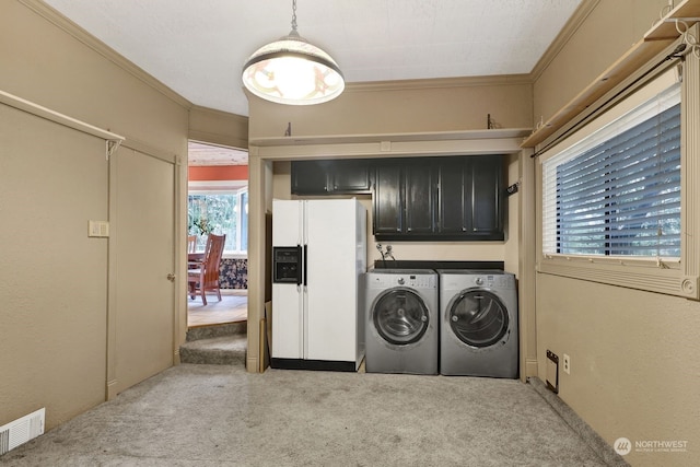 laundry area featuring cabinets, washing machine and clothes dryer, crown molding, and light carpet