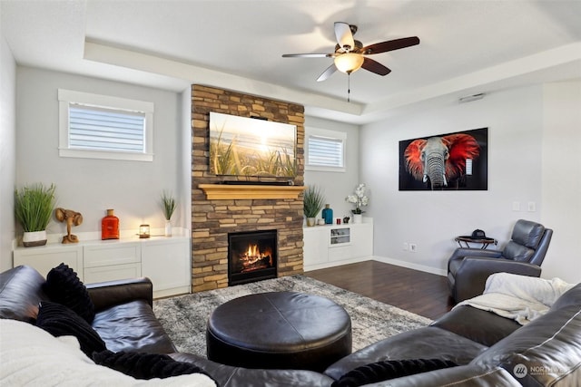 living room with hardwood / wood-style floors, a fireplace, a raised ceiling, and ceiling fan