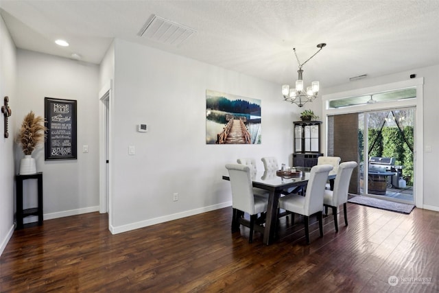 dining space featuring dark wood-type flooring, an inviting chandelier, and a textured ceiling