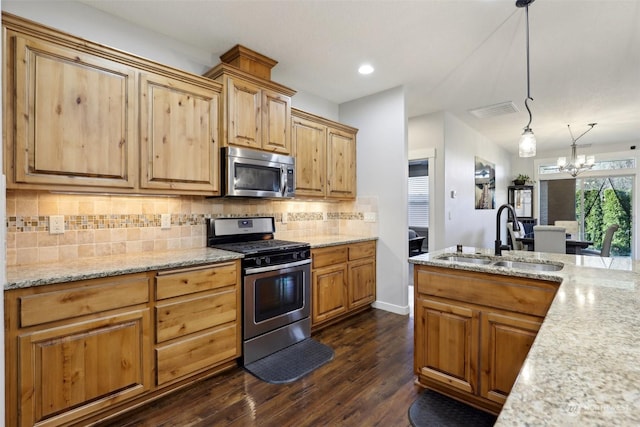 kitchen with sink, dark wood-type flooring, hanging light fixtures, stainless steel appliances, and tasteful backsplash