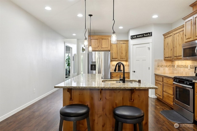 kitchen featuring sink, a kitchen breakfast bar, hanging light fixtures, stainless steel appliances, and light stone countertops