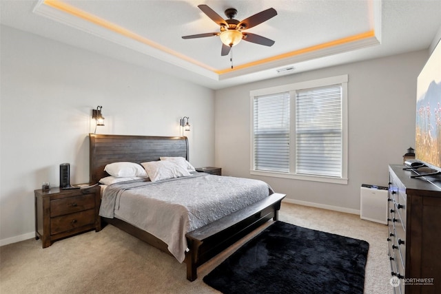 carpeted bedroom with a tray ceiling and ceiling fan