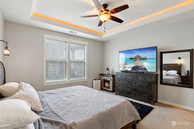 carpeted bedroom with ceiling fan and a raised ceiling