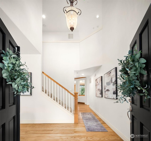 foyer entrance with a high ceiling and light hardwood / wood-style floors