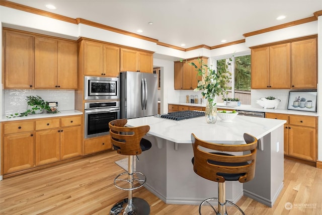 kitchen with stainless steel appliances, a breakfast bar, a kitchen island, and light wood-type flooring