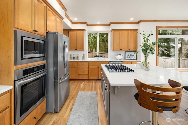 kitchen featuring crown molding, a healthy amount of sunlight, stainless steel appliances, and light hardwood / wood-style flooring