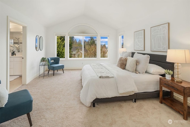 bedroom featuring lofted ceiling, light colored carpet, and ensuite bath