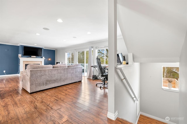 living room featuring hardwood / wood-style flooring, ornamental molding, and a tile fireplace