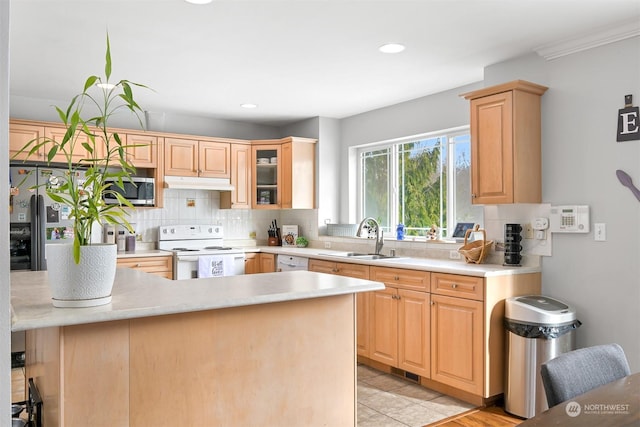 kitchen with a breakfast bar, sink, light brown cabinets, appliances with stainless steel finishes, and decorative backsplash