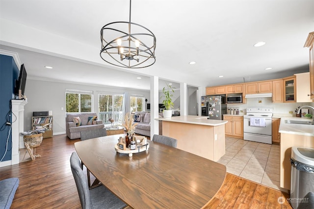 dining room featuring sink, a notable chandelier, and light wood-type flooring