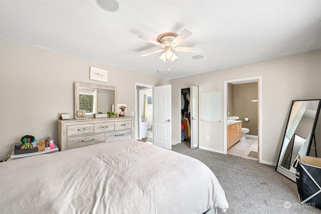 carpeted bedroom with ceiling fan, a walk in closet, ensuite bathroom, and a closet