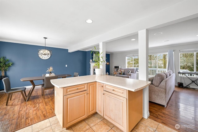 kitchen with pendant lighting, crown molding, light brown cabinetry, and light wood-type flooring