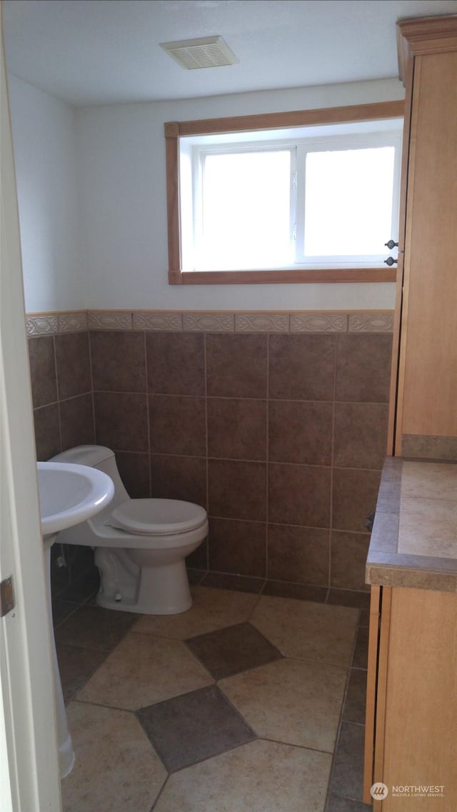 bathroom featuring tile walls and toilet