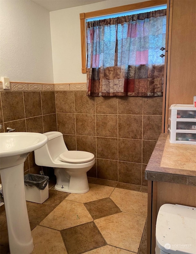 bathroom featuring toilet and tile walls