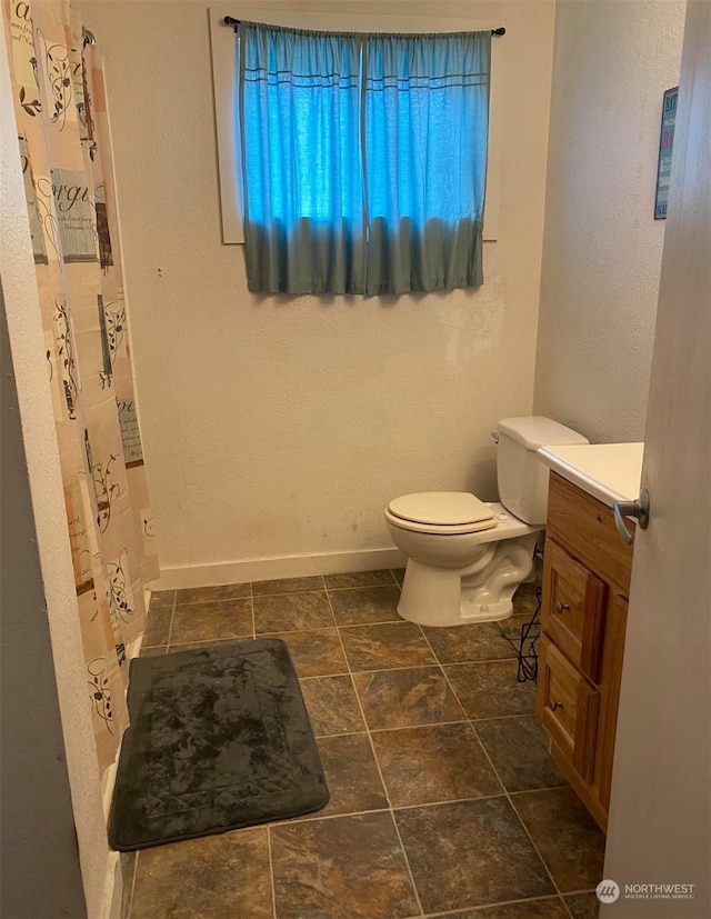 bathroom featuring vanity, curtained shower, and toilet