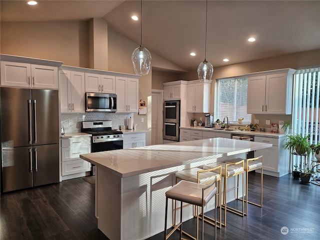 kitchen featuring sink, a center island, appliances with stainless steel finishes, pendant lighting, and white cabinets