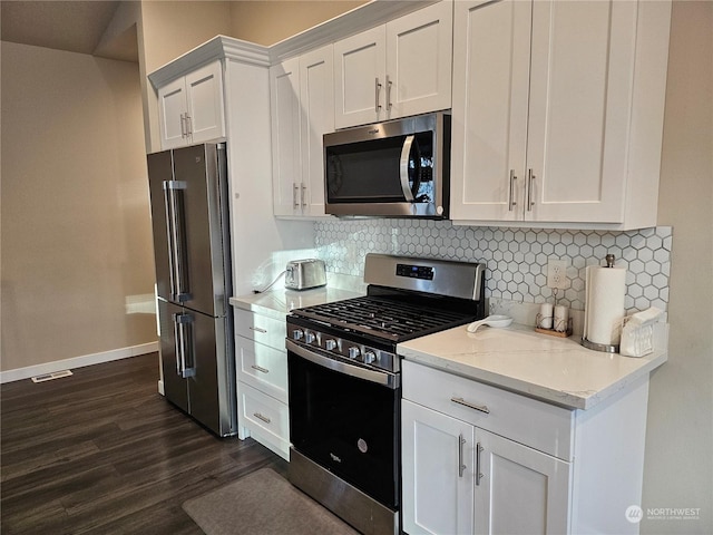 kitchen featuring white cabinetry, appliances with stainless steel finishes, light stone countertops, and decorative backsplash