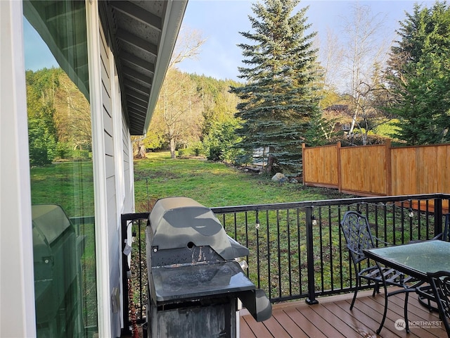 wooden terrace featuring a grill and a yard