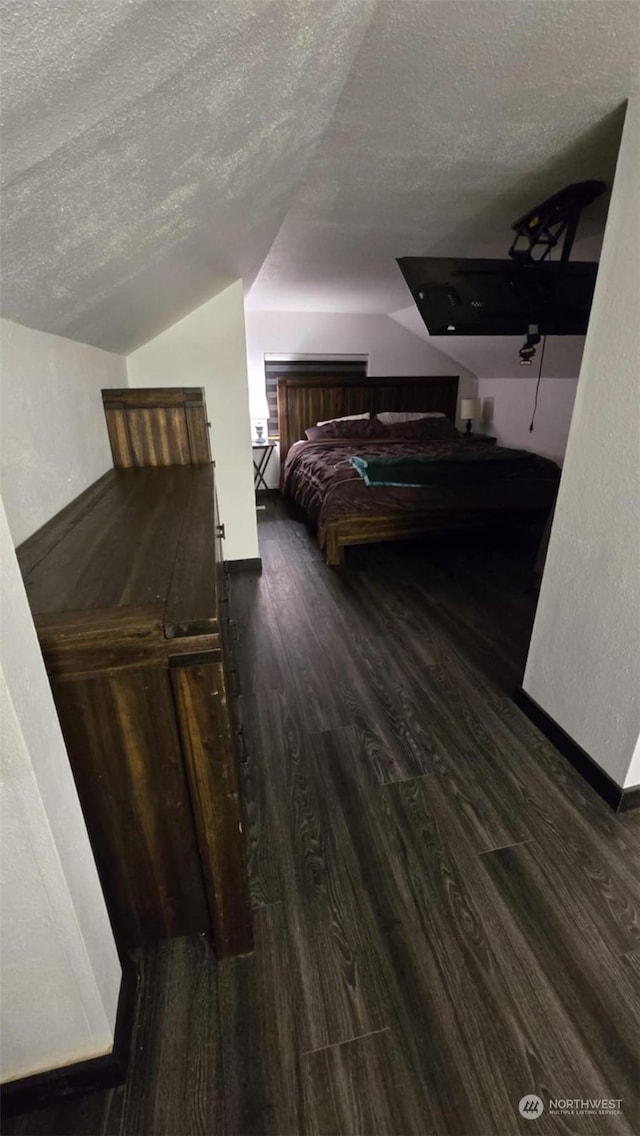 bedroom with dark hardwood / wood-style flooring, vaulted ceiling, and a textured ceiling