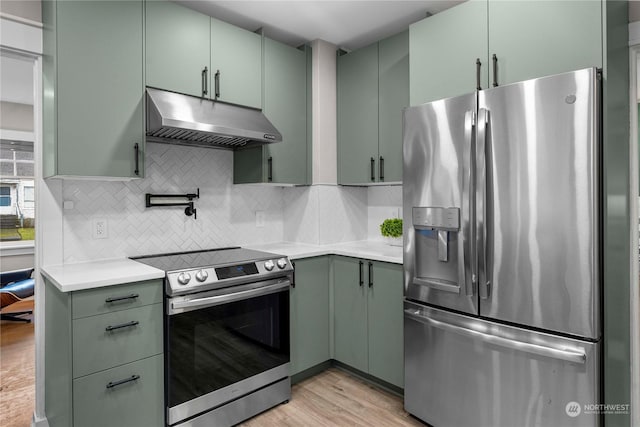 kitchen with under cabinet range hood, green cabinetry, appliances with stainless steel finishes, and light countertops