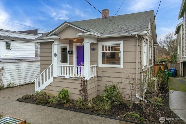 bungalow featuring a chimney and a shingled roof