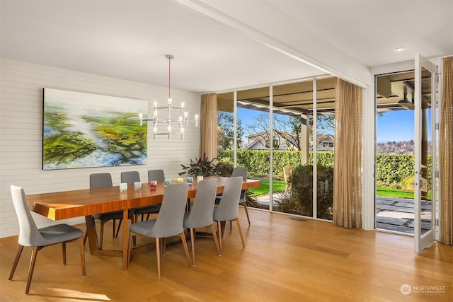 dining room featuring light hardwood / wood-style flooring, expansive windows, and a chandelier