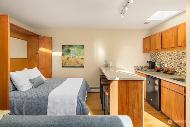 bedroom featuring a skylight, sink, light hardwood / wood-style floors, and baseboard heating