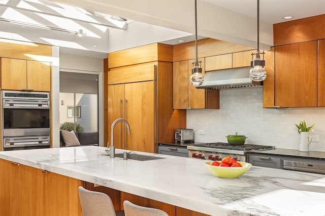 kitchen featuring decorative light fixtures, sink, dark stone counters, paneled refrigerator, and stainless steel double oven