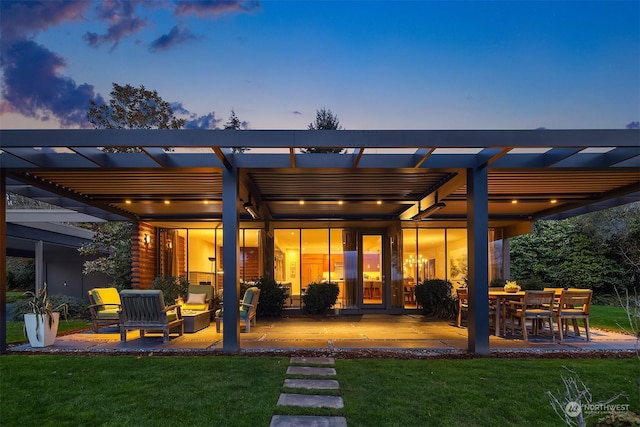 back house at dusk with a pergola, a wooden deck, a yard, and an outdoor hangout area