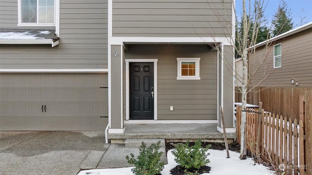 snow covered property entrance featuring a garage