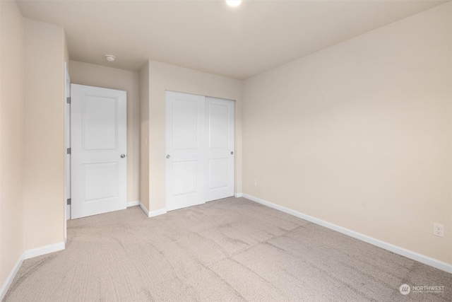 unfurnished bedroom with light colored carpet and a closet