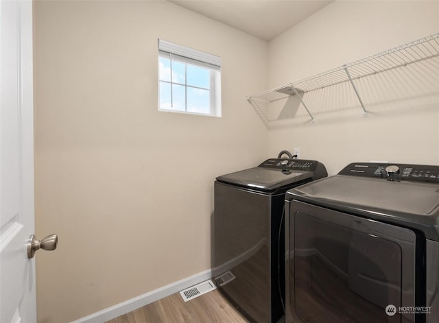 laundry area with washer and dryer and light hardwood / wood-style floors