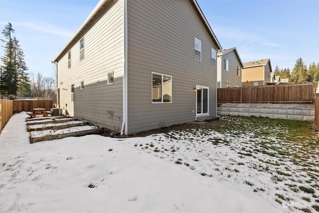 snow covered back of property featuring central air condition unit