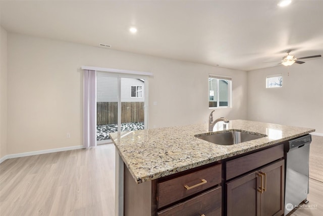 kitchen with light stone counters, sink, stainless steel dishwasher, and light hardwood / wood-style floors