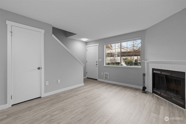 unfurnished living room featuring light wood-type flooring and a fireplace