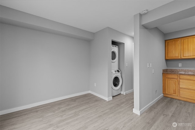 laundry room with stacked washer / drying machine and light hardwood / wood-style flooring